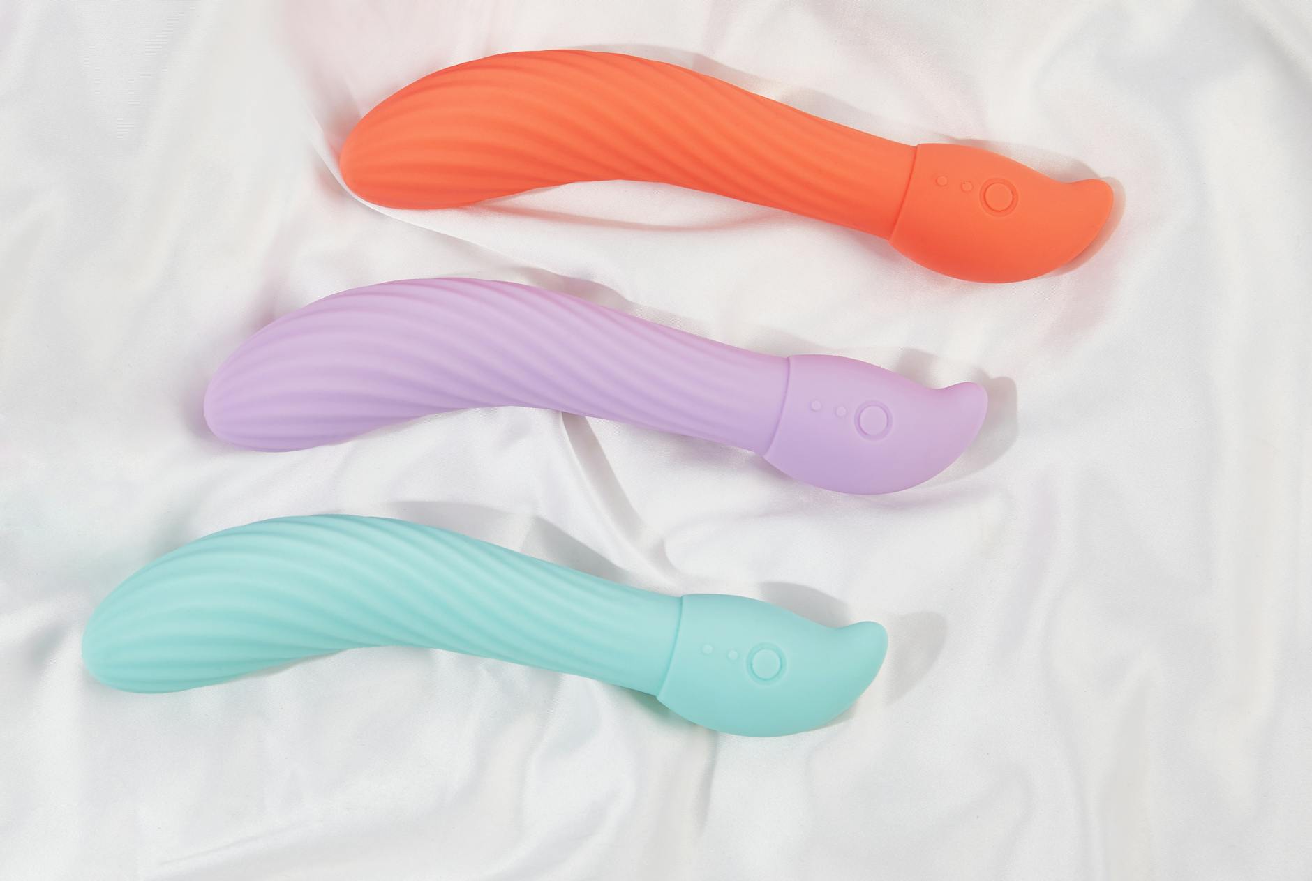 A stylish teal vibrator on smooth white silk fabric, symbolizing elegant intimacy