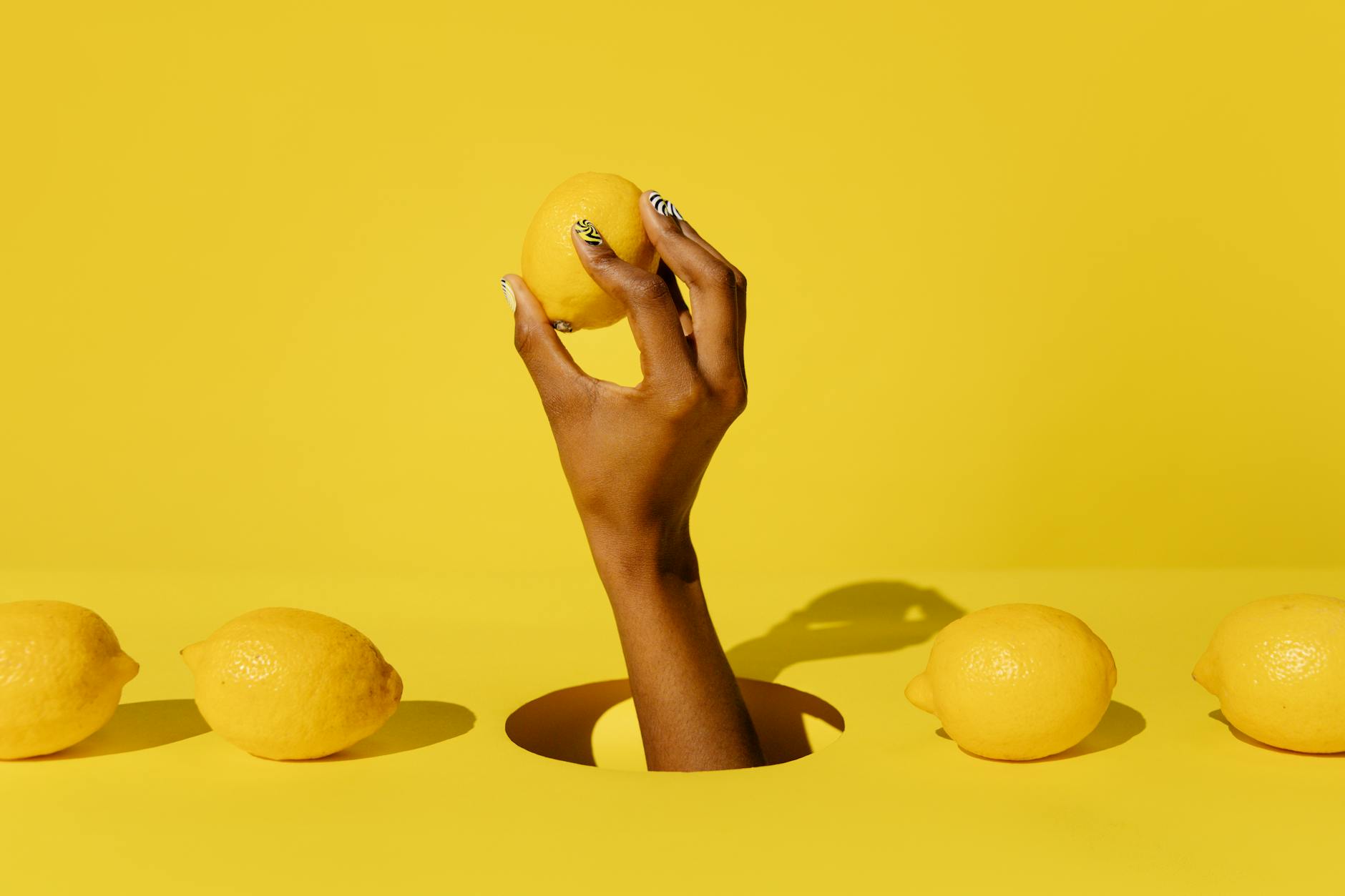 Close-up of a hand holding an orange vibrator against a minimalistic purple backdrop, showcasing modern sensuality
