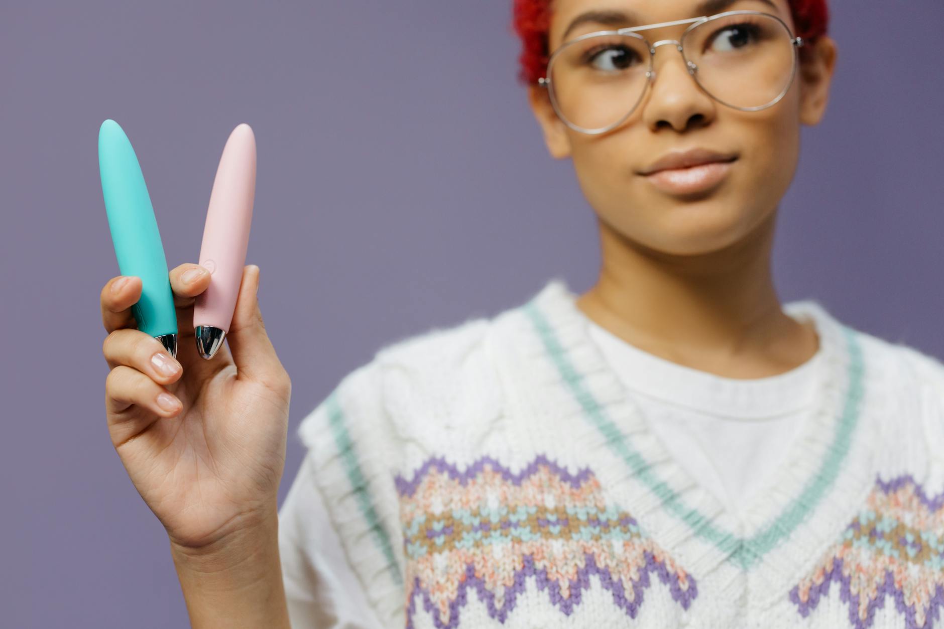 Woman holding colorful vibrators against purple background